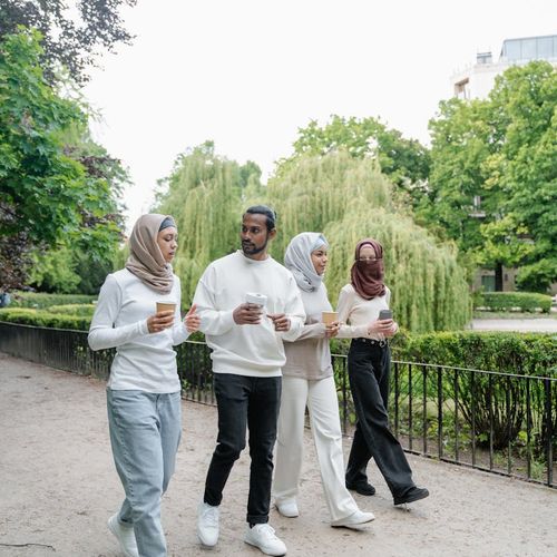 A group of diverse people walking briskly in a park setting.