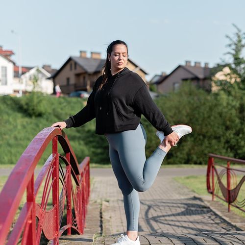 Person stretching gently outdoors with a calm and focused look.